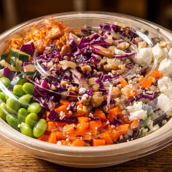 Colorful salad bowl with edamame, zucchini, red cabbage, carrots, and feta cheese.